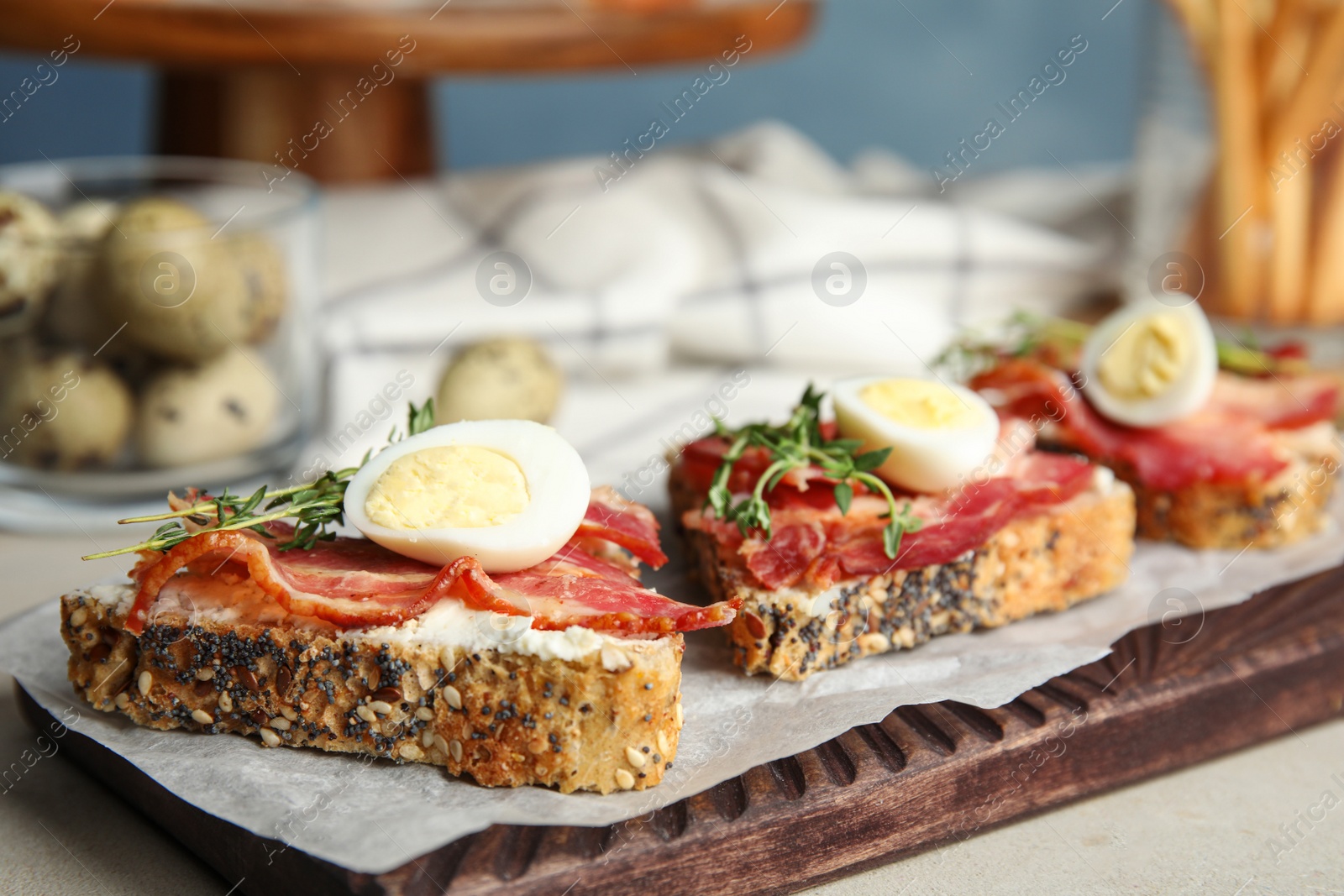 Photo of Cutting board of delicious bruschettas with prosciutto on table