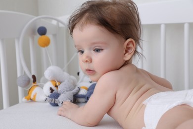 Photo of Cute little baby lying in comfortable crib at home, space for text