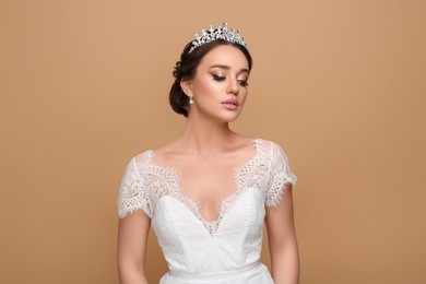 Photo of Beautiful young woman wearing luxurious tiara on beige background