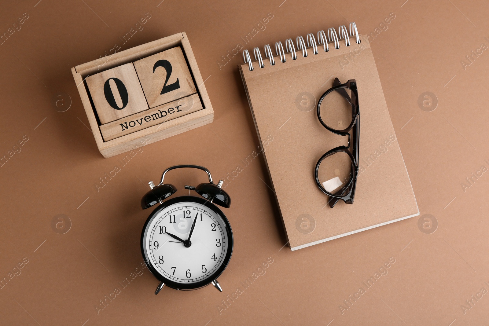 Photo of Wooden block calendar, notebook and alarm clock on background, flat lay
