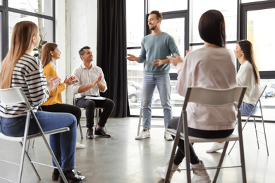 Photo of Psychotherapist working with patients in group therapy session indoors