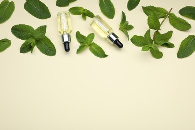 Bottles of essential oil and mint on beige background, above view. Space for text