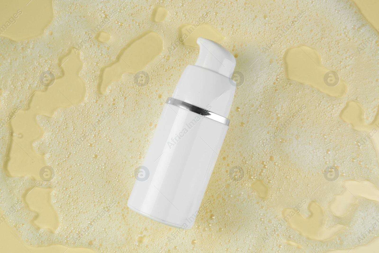 Photo of Bottle of face cleanser and white foam on beige background, top view. Skin care cosmetic