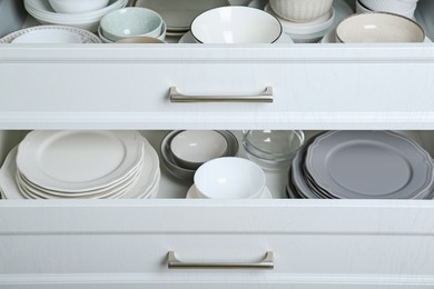 Photo of Open drawers with different plates and bowls, closeup