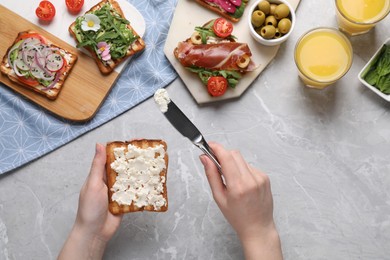 Photo of Woman cooking sandwich at light marble table, top view