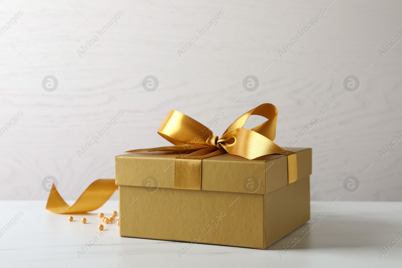 Photo of Beautiful golden gift box and decor on white table