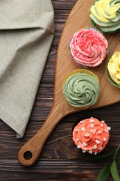 Delicious cupcake with bright cream on wooden table, flat lay