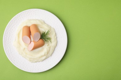 Photo of Delicious boiled sausages, mashed potato and dill on green background, top view. Space for text