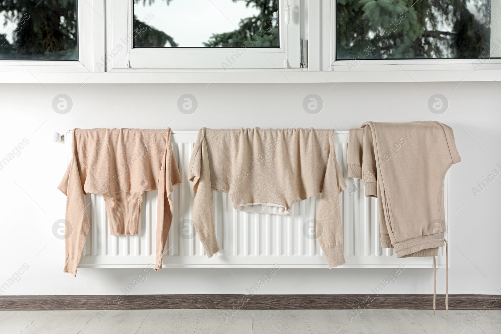 Photo of Clean clothes hanging on white radiator in room