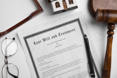 Photo of Last will and testament near house model, glasses, gavel on white table, flat lay