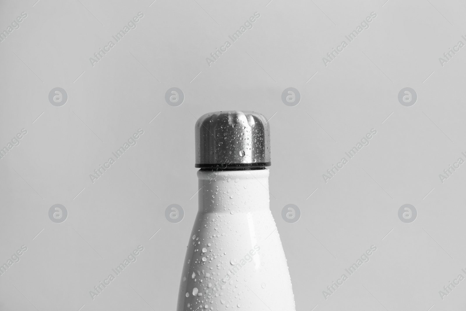 Photo of Stylish white thermo bottle with water drops on light grey background, closeup