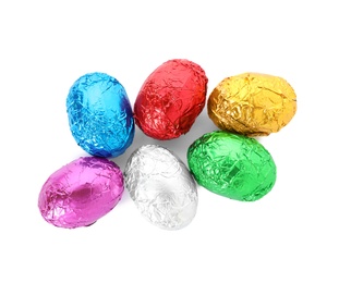 Photo of Many chocolate eggs wrapped in bright foil on white background, top view