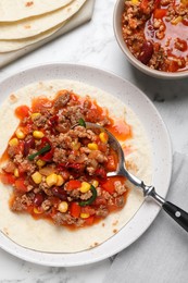 Tasty chili con carne with tortilla on white marble table, flat lay