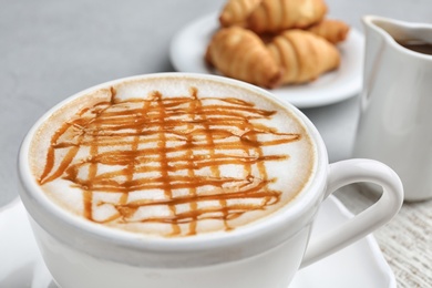 Cup of tasty caramel macchiato on table, closeup