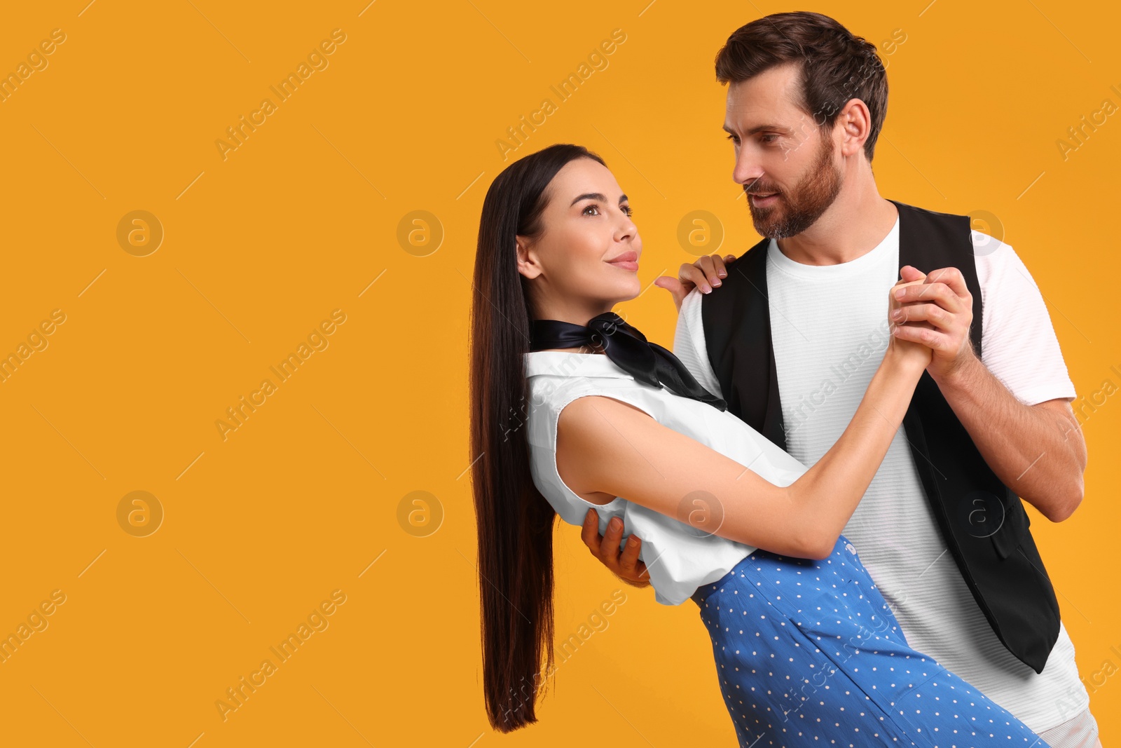Photo of Beautiful couple dancing together on orange background, space for text