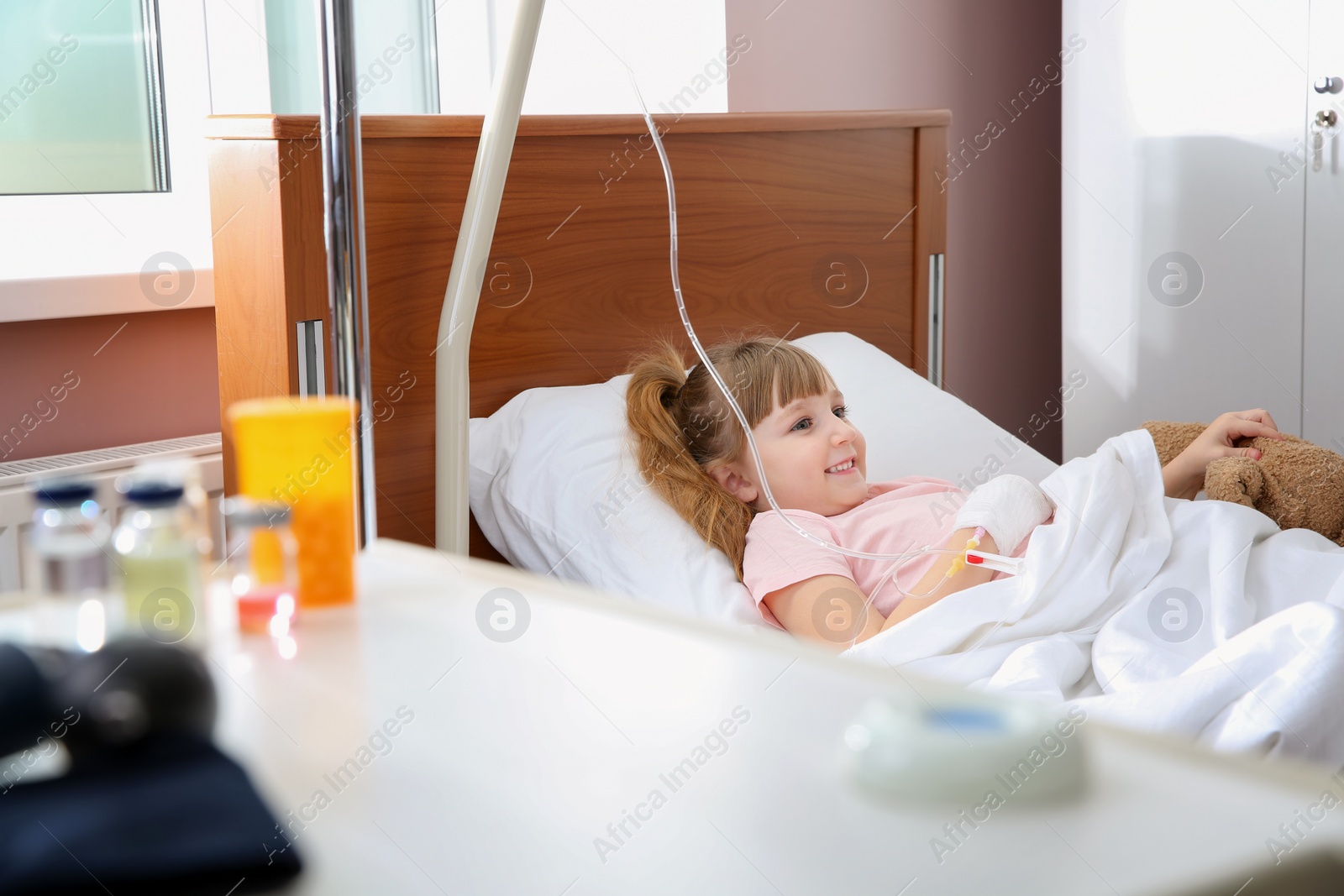 Photo of Little child with intravenous drip in hospital bed