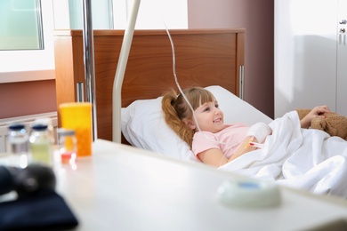 Photo of Little child with intravenous drip in hospital bed