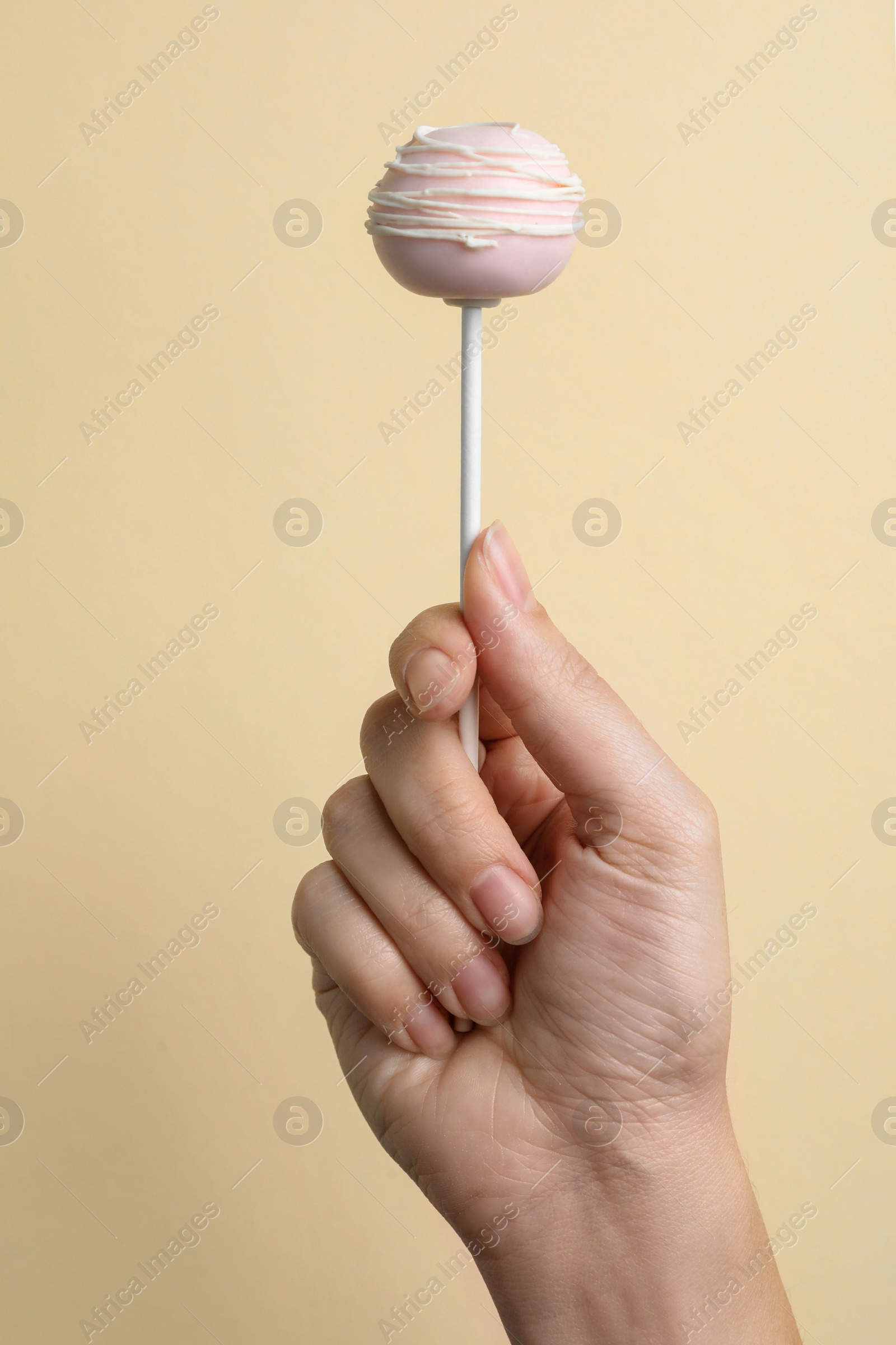 Photo of Woman holding sweet cake pop on light background, closeup