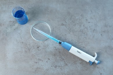 Photo of Laboratory analysis. Micropipette, petri dish and beaker on grey table, top view