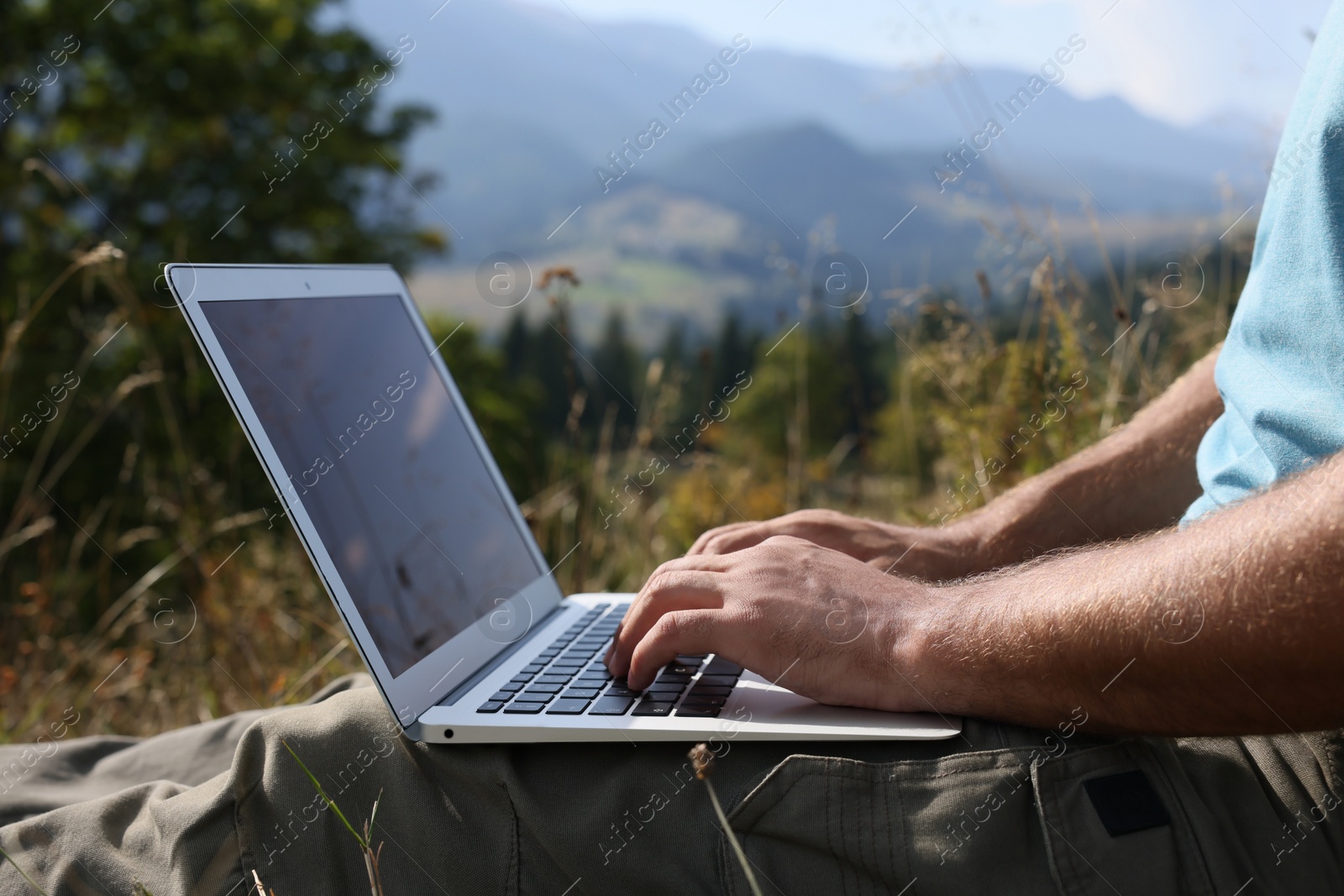 Photo of Man working with laptop outdoors on sunny day, closeup