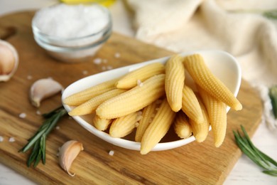 Photo of Fresh baby corn cobs on wooden board, closeup