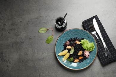 Photo of Delicious black risotto with seafood served on grey table. Space for text