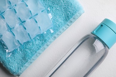Photo of Bottle of water, ice pack and towel on white background, flat lay. Heat stroke treatment