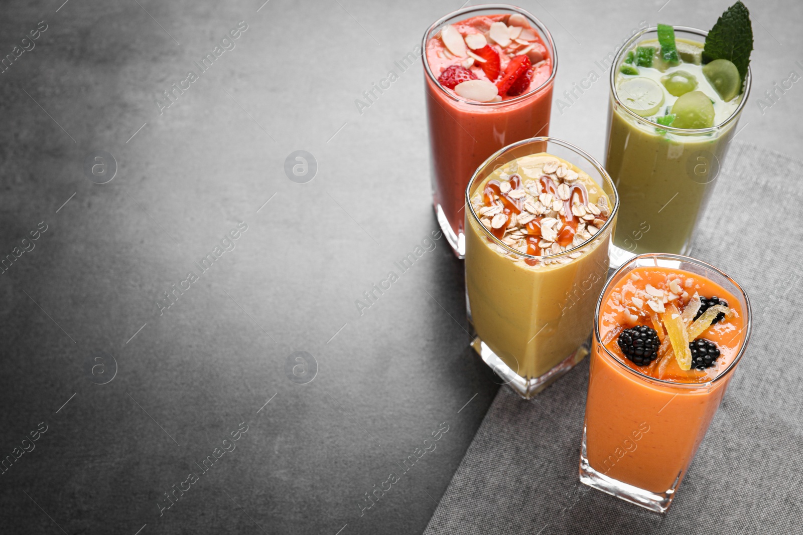 Photo of Many different delicious smoothies on grey table, above view. Space for text