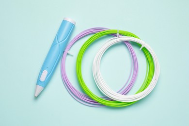 Stylish 3D pen and colorful plastic filaments on light blue background, flat lay