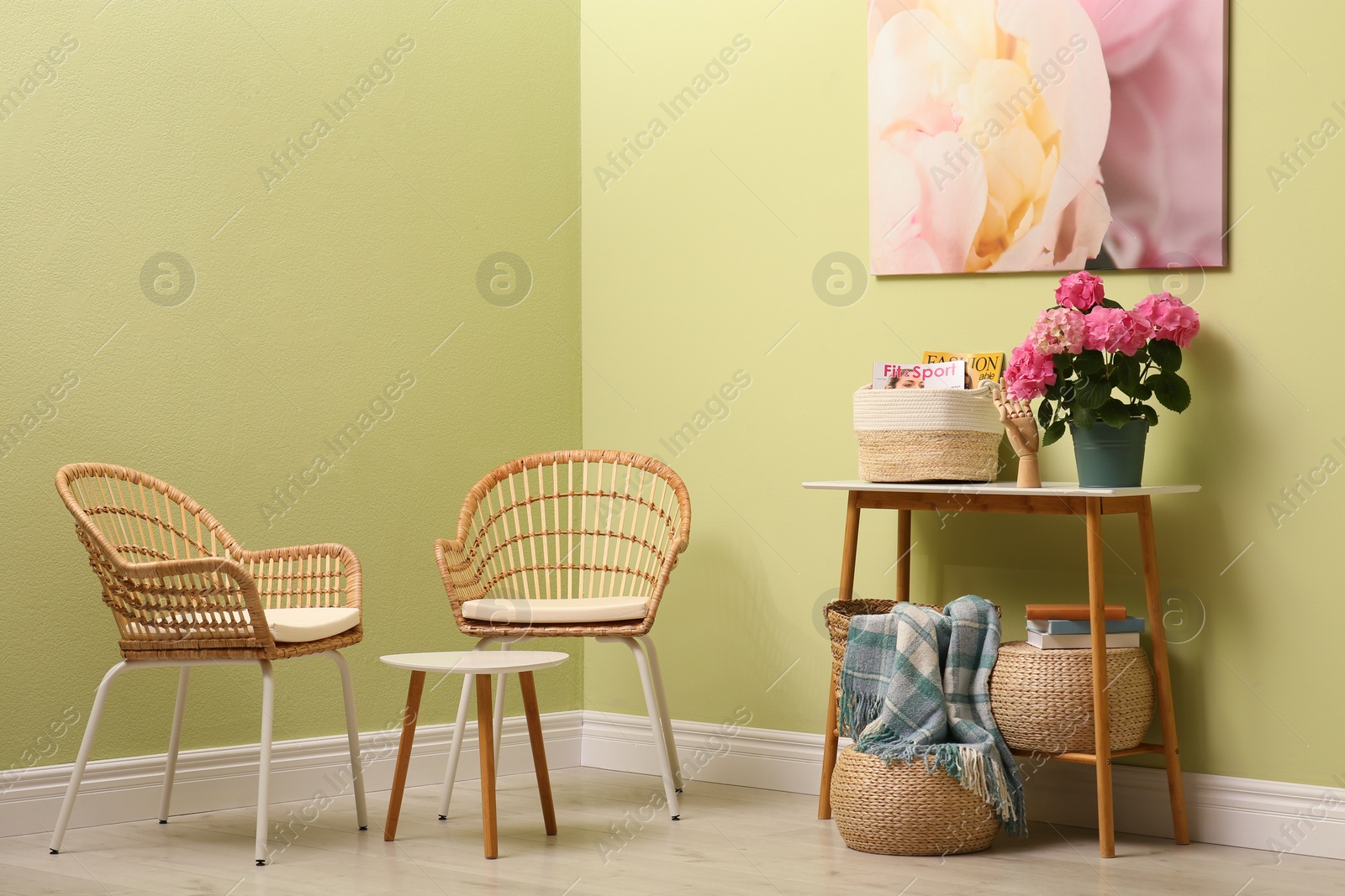 Photo of Modern hallway interior with beautiful hortensia flower on console table near wicker armchairs