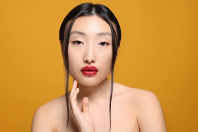 Portrait of beautiful young Asian woman on orange background