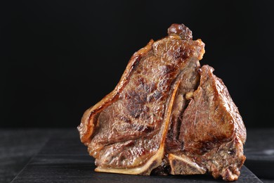 Photo of Delicious fried beef meat on table against black background