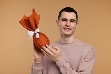 Easter celebration. Handsome young man with wrapped gift on beige background