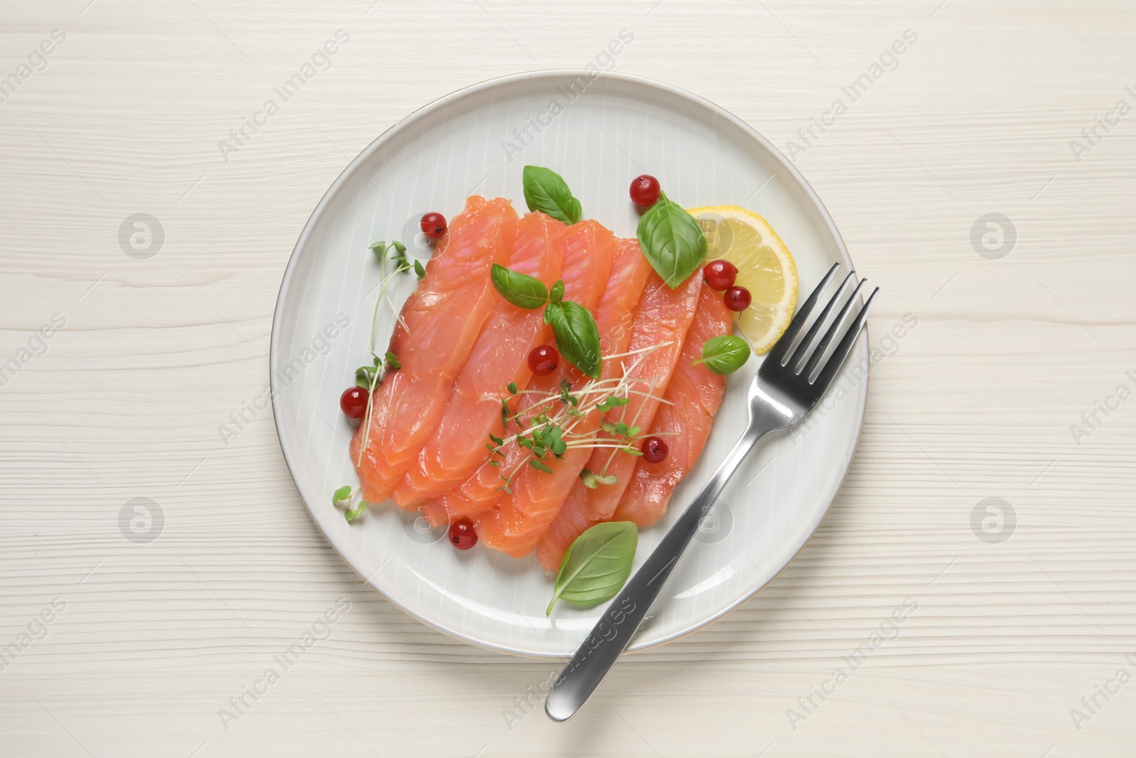 Photo of Delicious salmon carpaccio served on white wooden table, top view