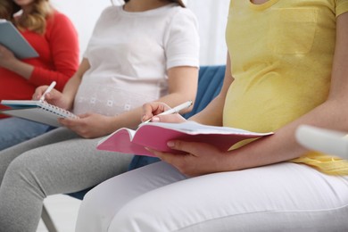 Photo of Group of pregnant women at courses for expectant mothers on blurred background, closeup
