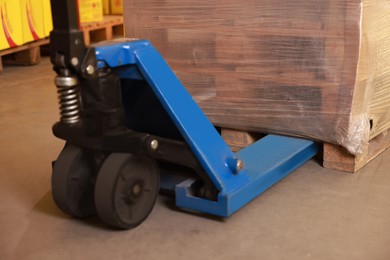 Wooden pallets wrapped in stretch on manual forklift indoors, closeup