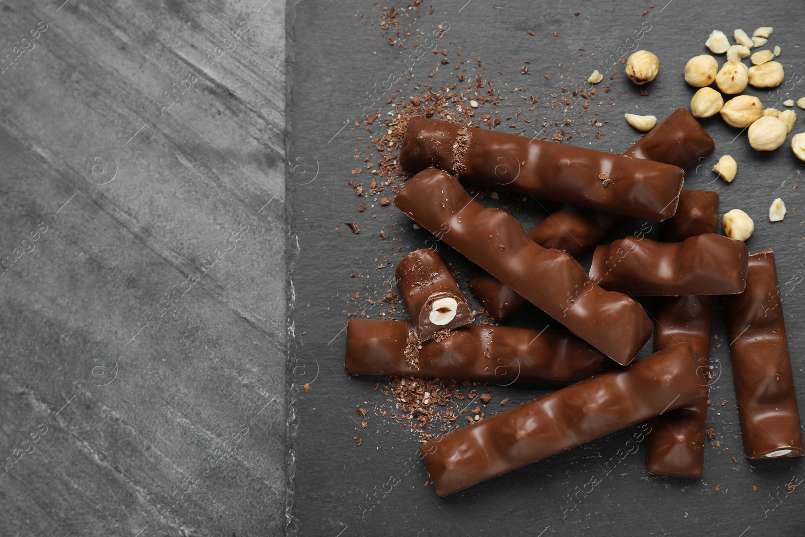 Photo of Tasty chocolate bars with nuts on black table, top view. Space for text