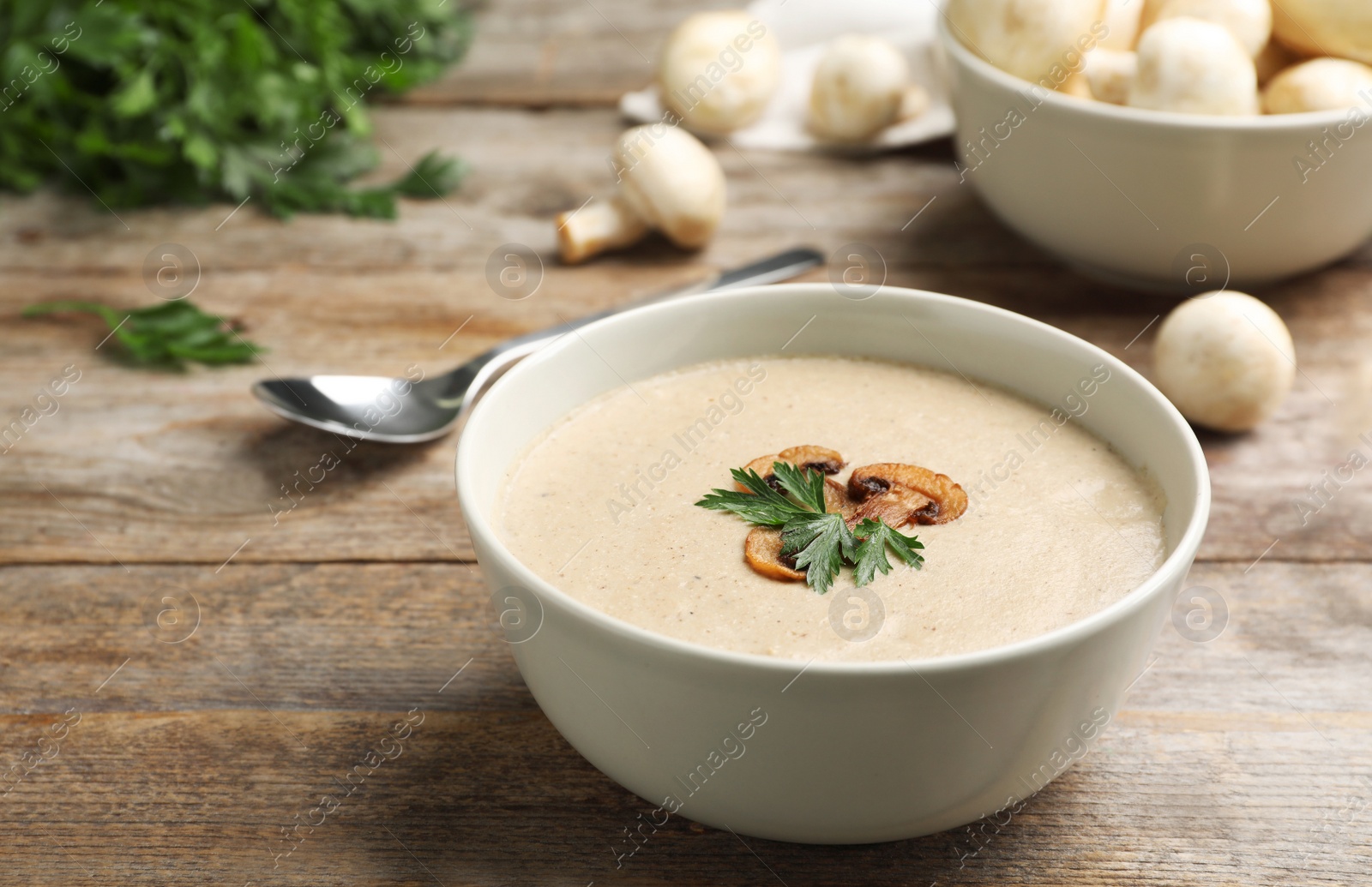 Photo of Bowl of fresh homemade mushroom soup on wooden table