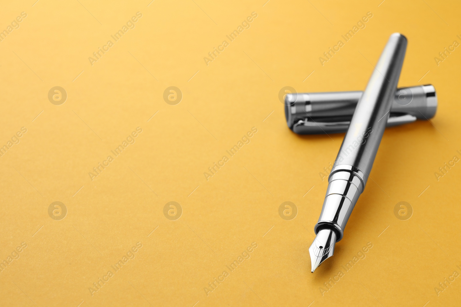 Photo of Stylish fountain pen with cap on yellow background, closeup. Space for text