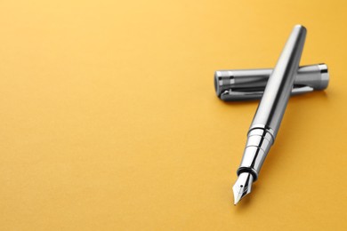 Photo of Stylish fountain pen with cap on yellow background, closeup. Space for text