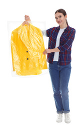 Young woman holding hanger with jacket on white background. Dry-cleaning service