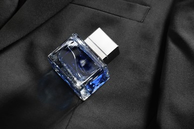 Photo of Luxury men's perfume in bottle on black jacket, space for text