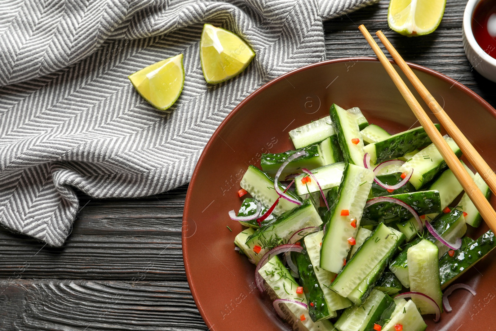 Photo of Plate with delicious cucumber salad served on wooden table, top view