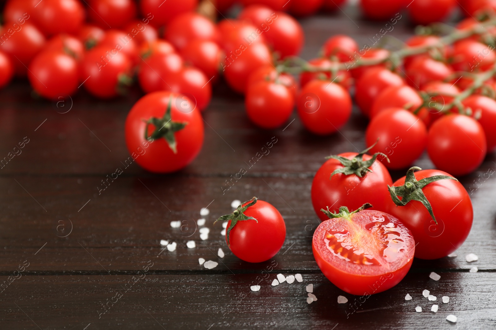 Photo of Fresh cherry tomatoes and sea salt on wooden table