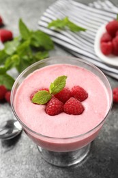 Photo of Delicious raspberry mousse with mint on grey table