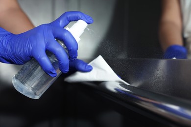 Photo of Woman wiping elevator`s handrails with detergent, closeup