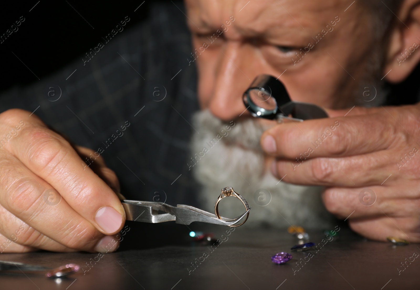 Photo of Male jeweler evaluating diamond ring in workshop, closeup view