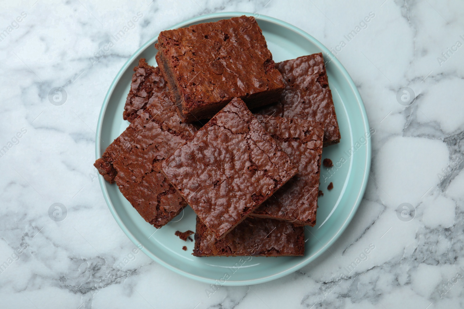 Photo of Delicious chocolate brownies on white marble table, top view