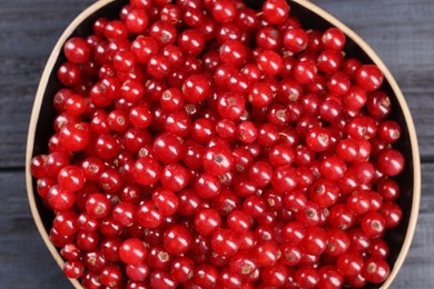 Ripe red currants in bowl on wooden rustic table, top view