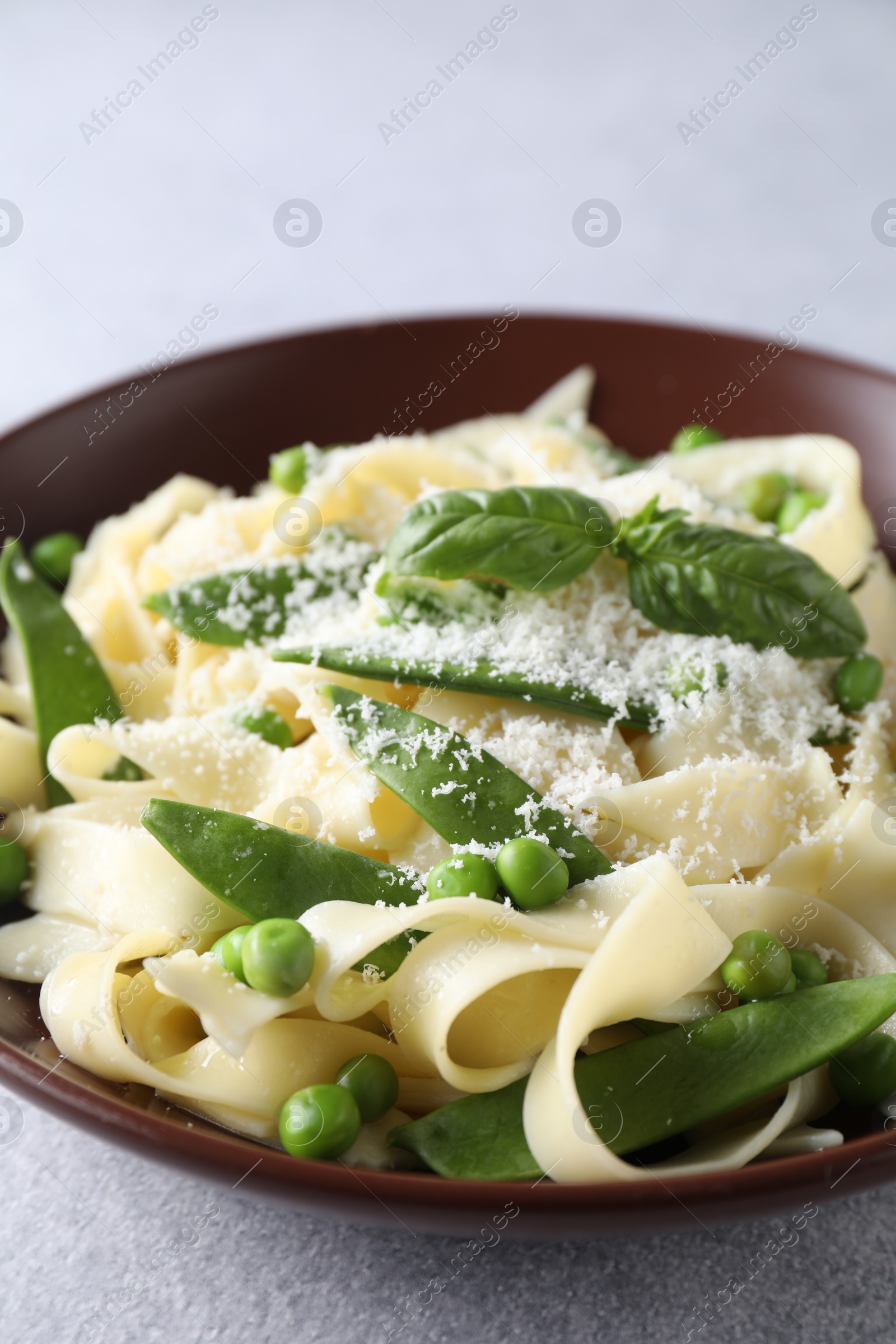 Photo of Delicious pasta with green peas and cheese on grey table, closeup